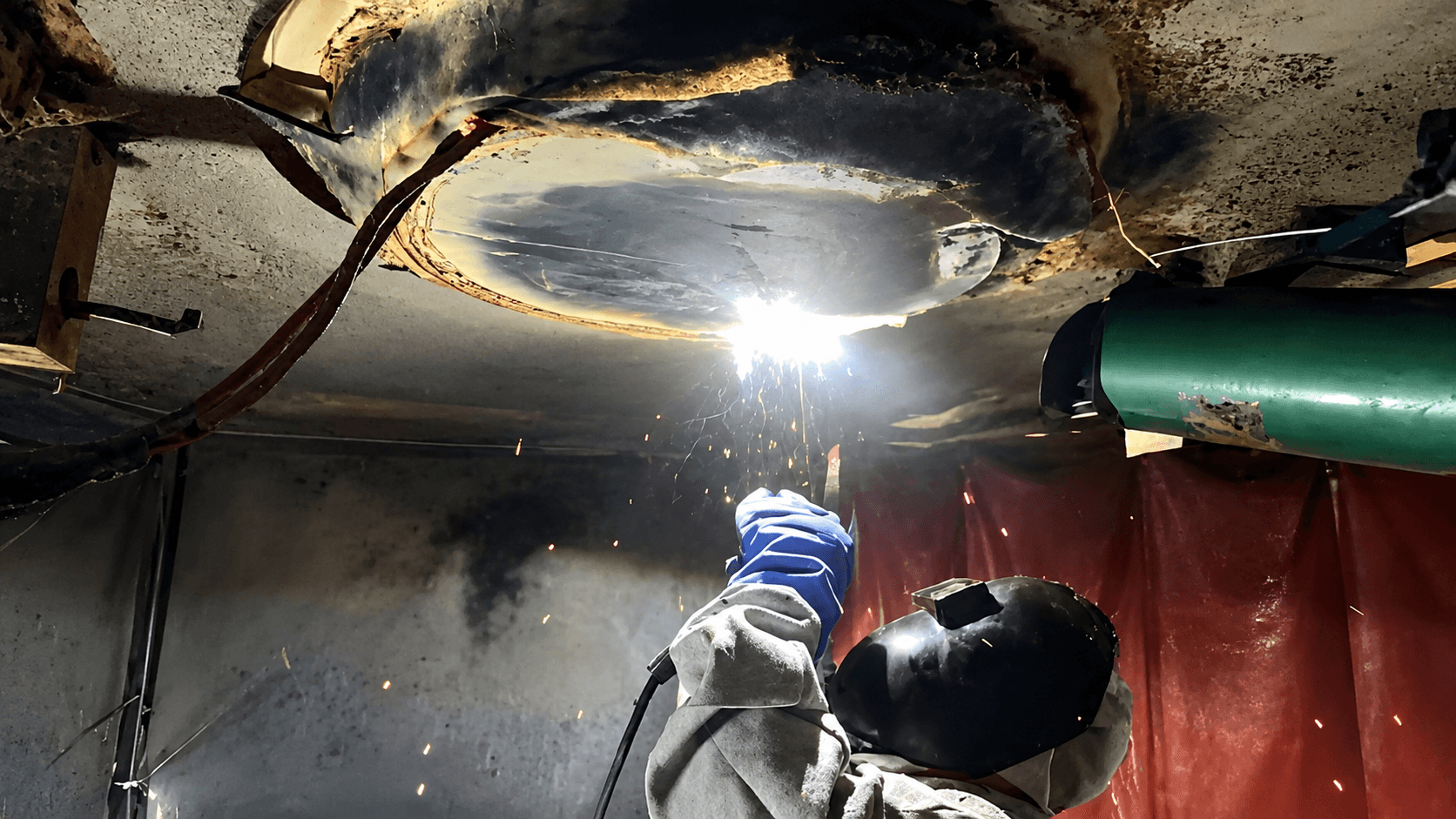 Soldador realiza manutenção de peça em solda sobre cabeça
